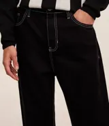 Pantalón baggy negro de sarga de algodón, con cintura fija con trabillas, botón contrastante y cierre por cremallera oculto, bolsillos laterales y traseros. Modelo holgado de corte recto y ancho.