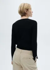 Cárdigan negro de punto fino con cuello redondo y cierre frontal con botones blancos.
