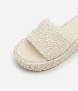 Sandalia flatform con superficie trenzada metalizada color dorado, sin cierre, con tira ancha y puntera redonda.