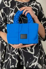 Cartera de tela color azul con asas torneadas y bolsillo interior, con opción de uso como bandolera.