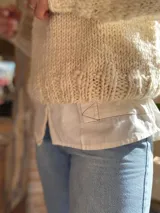Sweater tejido de lana merino color crudo, con cuello alto y mangas largas abullonadas. Tejido artesanal con punto grueso.