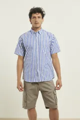 Camisa de manga corta a rayas verticales azules y blancas, con cuello abotonado y bolsillo en el pecho.