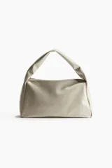 Cartera color crema de tejido revestido con cierre superior y asa ancha.