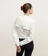 Campera deportiva estilo rompevientos cropped, color blanco, con capucha y cierre frontal.