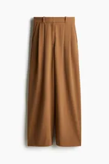 Pantalón ancho color marrón claro con pinzas, bolsillos laterales y trabillas para cinturón.