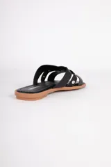 Sandalias bajas de símil cuero con punta cuadrada, cintas caladas y tachas sobre el empeine.