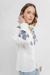 Camisa de manga larga en algodón liviano, color azul marino, con bordados florales en contraste en el frente y mangas. Cuello mao con terminación en ondas y puños fruncidos.
