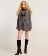 Blazer gris de sastrería, corte oversized, con cuello con solapas, manga larga y bolsillos frontales.