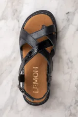Sandalias de cuero negro con tiras cruzadas y hebilla al tobillo.