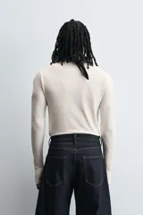 Camiseta de manga larga color crudo, corte ajustado y cuello redondo. Tiene aberturas en los puños y efecto lavado.