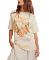 Remera color crema con estampado de flores de amapola color naranja y texto en la parte delantera.