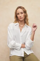 Camisa blanca de manga larga con botones a tono y puños de tres botones, diseño clásico.