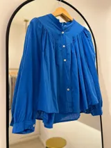 Camisa azul francia de manga larga con puño, cuello mao y cierre frontal con botones.
