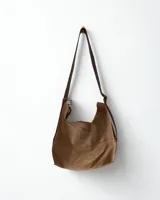 Cartera marrón de cuero con flecos y doble asa circular metálica.
