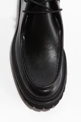 Zapato tipo bota de caña baja para hombre en color negro, con costura frontal estilo mocasín y cierre de cordones. Cuenta con una suela gruesa dentada y forro interior de algodón.
