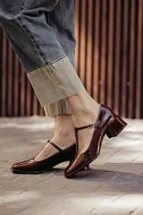 Zapato tipo T-bar color borgoña de charol, con taco bajo cuadrado y hebilla ajustable.