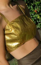 Top de cuero dorado, con un diseño versátil y ajuste cómodo.