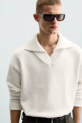 Sweater color crema de punto con cuello polo y escote en V.