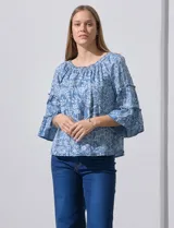 Blusa celeste con estampado floral blanco, escote con frunces y mangas 3/4 con volados.