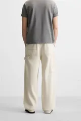 Pantalón de jean color crudo, corte relaxed fit, con bolsillos frontales y traseros tipo parche. Tiene tira multifunción y bolsillo tipo parche en las piernas.