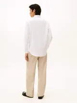 Camisa de manga larga blanca, confeccionada en algodón BCI, con cuello clásico y cierre de botones. Presenta un pequeño logo de Tommy Hilfiger bordado en el pecho.