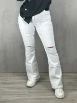 Jean blanco con rotura, corte flare y diseño de tiro medio.
