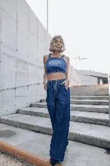 Conjunto de denim compuesto por un top corto con breteles anchos y un pantalón palazzo con cintura elastizada y bolsillos laterales.