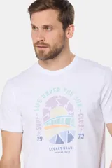 Remera blanca de manga corta con cuello redondo y un estampado gráfico frontal que simula un paisaje costero con un sol naciente o poniente, rodeado por texto circular que dice "SURF - LIFE UNDER THE SUN - CLUB".