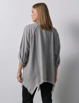 Camisa celeste de tencel, corte amplio, con cuello mao, escote en V y abotonadura frontal. Tiene bolsillos aplicados en el pecho, mangas 3/4 regulables con presilla y ruedo desflecado.