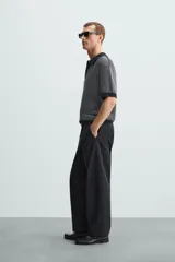 Polo de hombre de corte relajado, tejido de punto de algodón a rayas verticales en tonos gris y negro. Tiene cuello solapa, cierre frontal con botones y mangas cortas.