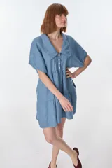 Vestido corto celeste de lino, con cuello tipo polo con detalle de puntilla, mangas cortas y falda escalonada con volantes.
