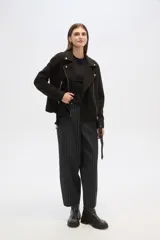 Chaqueta negra con cuello solapa, cierre cruzado con cremallera, cinturón con hebilla, bolsillos laterales con cremallera y detalles de botones metálicos.