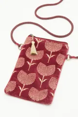 Bolso pequeño tipo cartera porta celular, confeccionado en terciopelo color borgoña con diseño bordado de tulipanes dorados. Tiene acceso superior con cierre y tirante en hilo metalizado, más cordón largo que permite colgarlo al cuerpo.