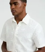 Camisa de hombre confeccionada en algodón, modelo comfort, color blanco con estampa bordada de flores. Posee cuello inglés, manga corta y abotonado delantero.