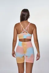 Conjunto deportivo de calza corta y top con estampado tie-dye en tonos salmón, celeste y amarillo. El top es de breteles finos y la calza es de tiro alto.
