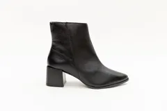 Bota de cuero negra, de caña corta y punta fina, con cierre lateral y taco geométrico de 6 cm.