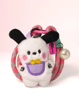 Llavero con mini peluche de perro blanco con orejas negras, babero lila y moño amarillo. Incluye correa de goma elástica en tonos rosa y celeste, dije de perla y mosquetón metálico rosa.