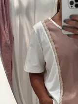 Remera blanca con panel central celeste, cuello redondo y mangas cortas. Presenta detalles de puntilla en el panel lateral.