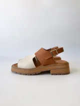 Sandalia de cuero color camel y crudo, con tira ancha sobre los dedos, tira al tobillo con hebilla y suela track.