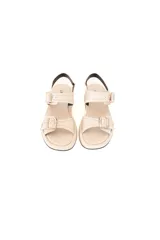 Sandalias planas de cuero color crema con múltiples correas ajustables con hebillas metálicas plateadas.