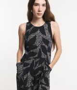 Mono largo sin mangas de viscosa twill color negro con estampado de follaje en blanco. Tiene cuello redondo, cierre con botón en la espalda y bolsillos laterales.