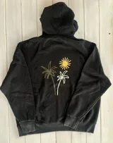 Hoodie negro con capucha y puños ajustados. Estampado en la espalda con dos palmeras y un sol en colores blanco, amarillo y verde oliva.