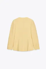 Blazer amarillo pálido de corte recto, con escote en pico y manga larga. Presenta bolsillos de ojal en el delantero y cierre frontal con botones a presión.
