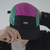 Gorra de cinco paneles con visera plana, color negro con secciones en verde y fucsia.