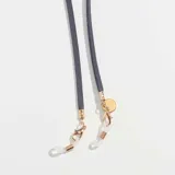 Correa para lentes color azul marino, de cuero sintético, con terminales dorados y logo grabado en chapa de acero inoxidable.