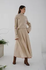 Sweater beige de lana con cuello redondo y mangas largas. Presenta detalles de bichos tejidos a contratono en la parte superior delantera.