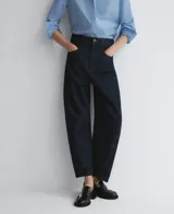 Pantalón de denim azul oscuro, corte barrel fit, con triple pespunte a contraste en interior y exterior de la pierna, cierre con botón metálico, trabillas y cinco bolsillos.