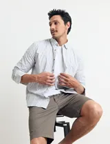 Camisa sport de algodón con cuello button-down y manga larga. Diseño a rayas verticales en tonos gris y blanco. Cierre frontal con botones de madera.