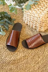 Sandalias tipo chinelas color marrón con textura símil cocodrilo.