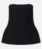 Blusa negra sin breteles, confeccionada en punto, con un recorte tipo peplum en el ruedo que le da volumen y movimiento.